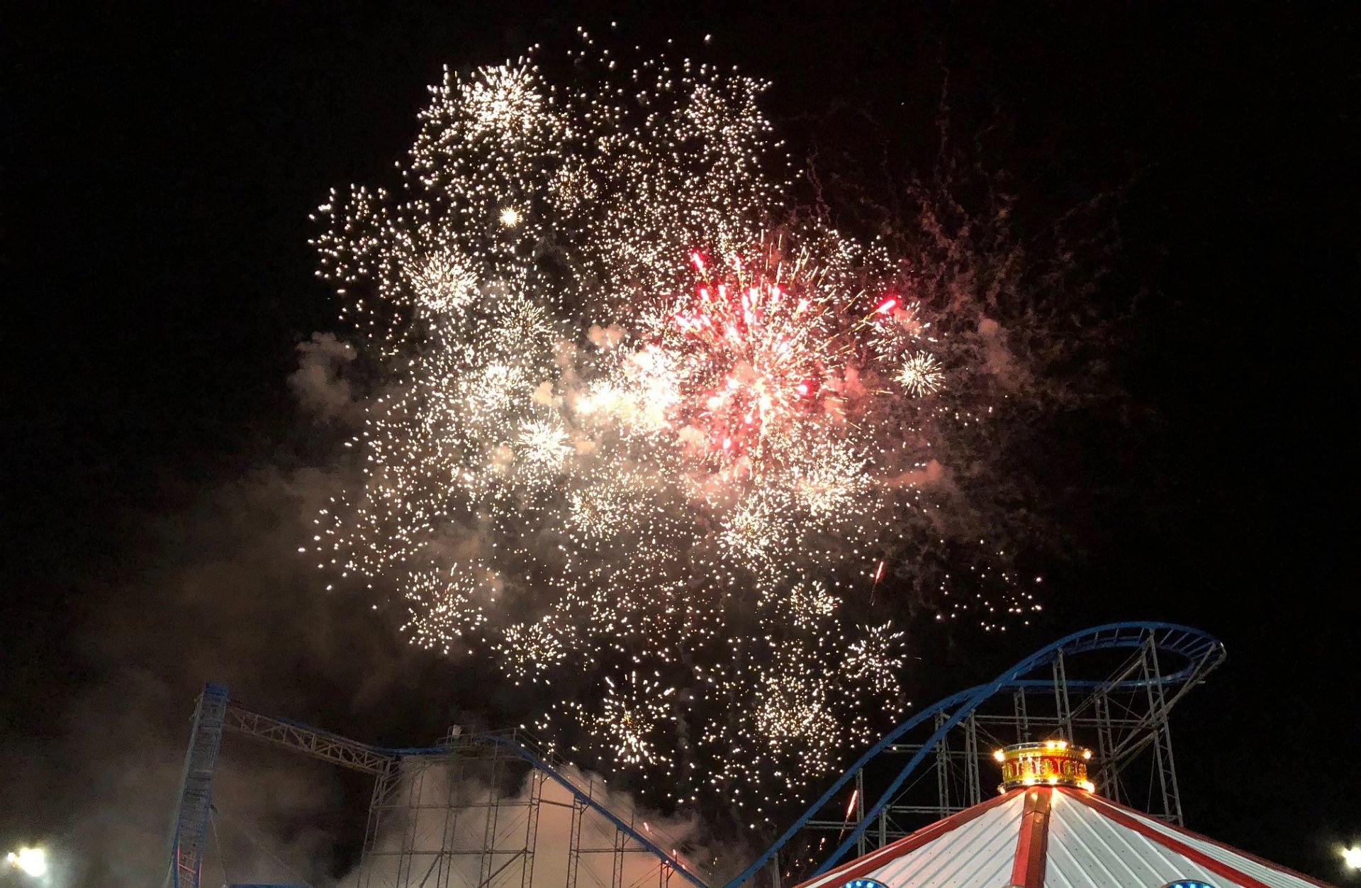 night sky with fireworks and roller coaster in background